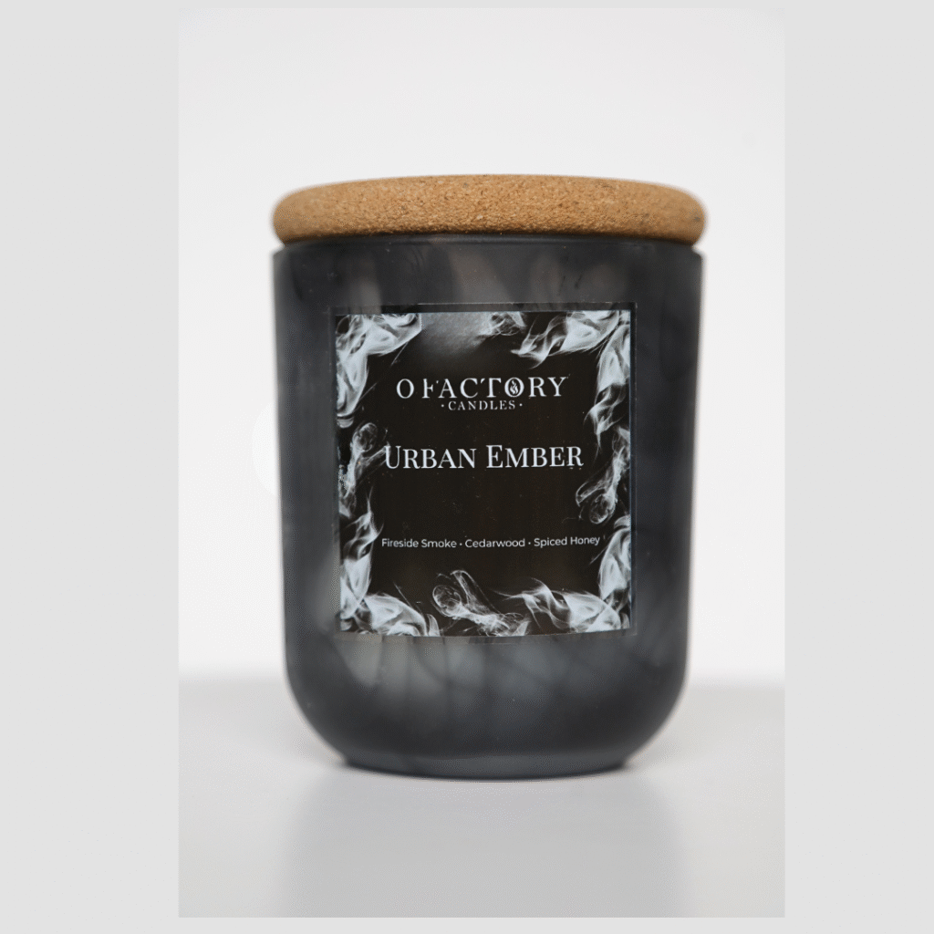 Urban Ember candle with fireside, cedarwood blanc, cinnamon stick, spiced honey, and tonka scent in black glass jar, hand-poured coconut apricot wax